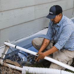 The image shows a man conducting an exterior HVAC inspection.